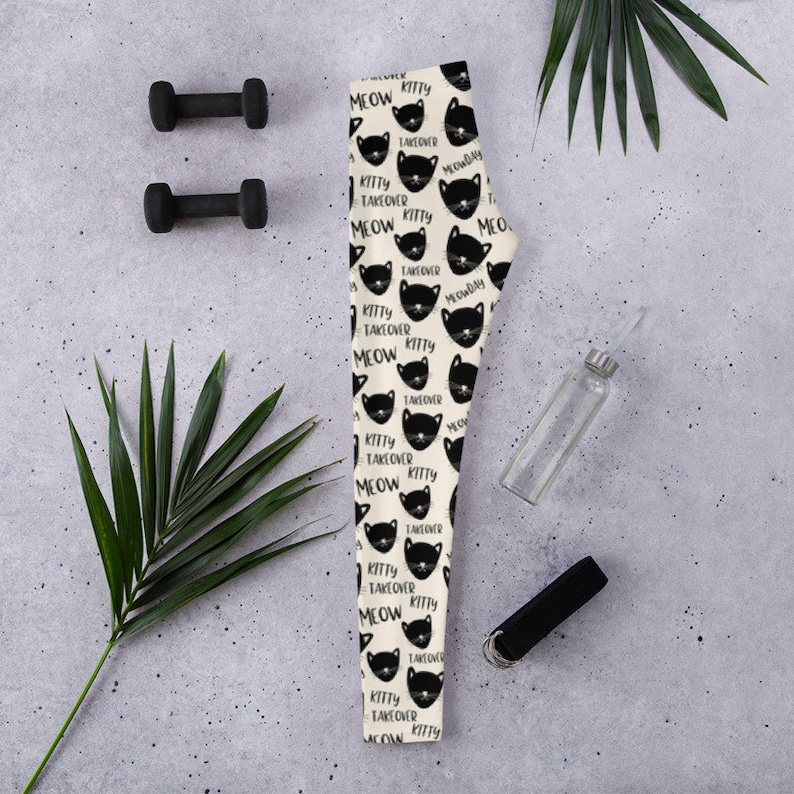 May include: Black and white leggings with a repeating pattern of black cats with the text "Meow Kitty Takeover" on a cream background.