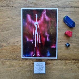 Può includere: Una stampa artistica raffigurante una figura bianca allungata con un dettaglio a forma di cuore su uno sfondo vibrante e colorato. Accompagnata da tre piccoli cristalli colorati e un adesivo con un disegno di funghi e la parola "MAEV3".