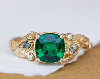 May include: A gold ring with a green gemstone and small diamonds set in a leafy design.