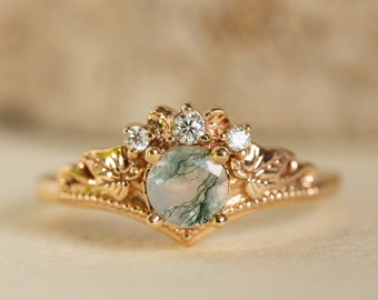 May include: A gold ring with a green moss agate gemstone surrounded by smaller diamonds. The ring has a delicate floral design.