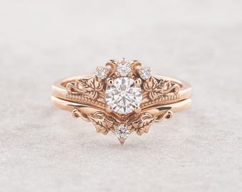 May include: A rose gold engagement ring with a round center stone and a delicate floral design. The ring is set with smaller diamonds around the center stone and on the band.