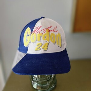 Puede incluir: Gorra de béisbol azul y blanca con el nombre "Gordon" en amarillo, el número "24" y una firma. La gorra tiene una visera azul y una corona blanca.