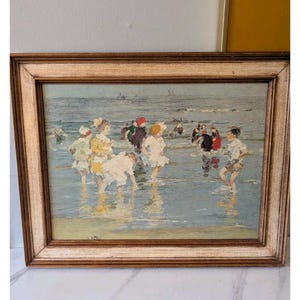 Puede incluir: Una pintura impresionista de niños jugando en el océano. La obra de arte presenta una paleta de colores azul claro y blanco, con un marco de madera. Los niños visten vestidos y sombreros blancos y amarillos, y están en el agua.