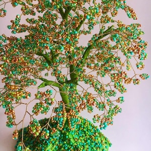 K&ouml;nnte beinhalten: Eine Perlen-Drahtbaum-Skulptur in Gr&uuml;n- und Goldt&ouml;nen. Der Baum besteht aus Draht und Perlen, und die Basis ist mit Perlen bedeckt.