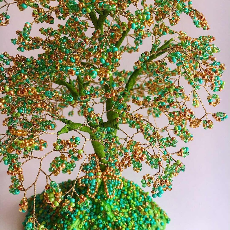 K&ouml;nnte beinhalten: Eine Perlen-Drahtbaum-Skulptur in Gr&uuml;n- und Goldt&ouml;nen. Der Baum besteht aus Draht und Perlen, und die Basis ist mit Perlen bedeckt.