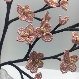 May include: A delicate pink beaded cherry blossom branch with yellow centres. The branch is made of wire and is perfect for adding a touch of spring to any home.