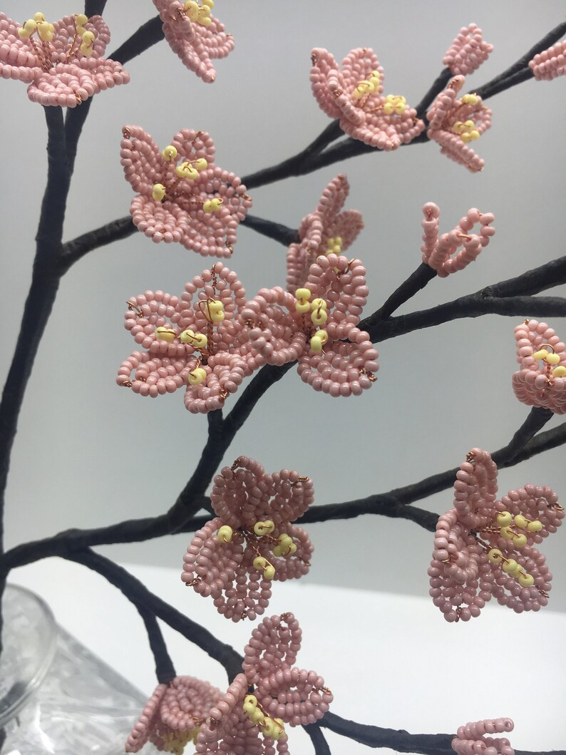 May include: A delicate pink beaded cherry blossom branch with yellow centres. The branch is made of wire and is perfect for adding a touch of spring to any home.