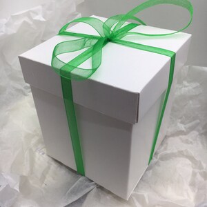 May include: A white gift box with a green ribbon tied in a bow.
