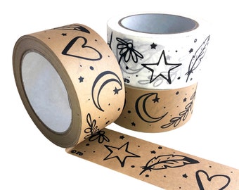 May include: Decorative washi tape rolls in kraft paper and white, featuring black celestial and floral designs. The designs include stars, moons, hearts, feathers, and flowers. The tape is ideal for scrapbooking, journaling, and crafting projects.