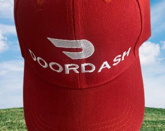 Op de afbeelding: Een felrode honkbalpet met het wit geborduurde DoorDash-logo en de tekst op het voorpaneel. De pet heeft een gestructureerde kroon, een gebogen klep en gestikte oogjes op de bovenste panelen voor een strak en uniform uiterlijk.