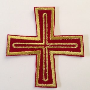 May include: A red cross with a gold border. The cross is embroidered with a gold outline.