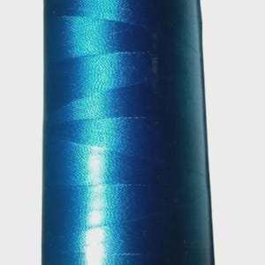 May include: A spool of vibrant blue embroidery thread. The thread is tightly wound on a white and gray spool, with the number "3330" printed on the base. The thread has a shiny, reflective quality.