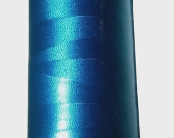 May include: A spool of vibrant blue embroidery thread. The thread is tightly wound on a white and gray spool, with the number "3330" printed on the base. The thread has a shiny, reflective quality.