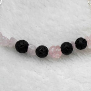 May include: A silver chain necklace with alternating black lava rock and pink rose quartz beads.