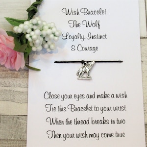 May include: A black string bracelet with a silver wolf charm. The card reads "Wish Bracelet The Wolf Loyalty. Instinct & Courage Close your eyes and make a wish Tie this Bracelet to your wrist When the thread breaks in two Then your wish may come true."