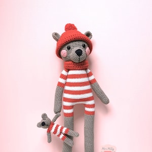 Op de afbeelding: Twee gehaakte teddyberen die rood-wit gestreepte outfits dragen. De grotere beer draagt ​​een rode hoed met een witte pompon. De kleinere beer houdt de hand van de grotere beer vast.