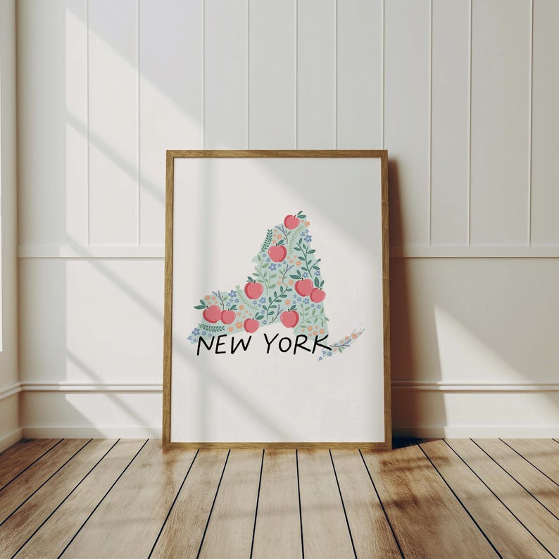 May include: A framed print of the state of New York, outlined in green leaves and pink apples. The text "NEW YORK" is printed below the outline.