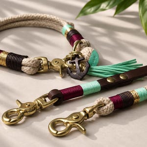 May include: A pet collar and leash set made of thick beige rope, featuring accents of mint green and deep burgundy thread, dark brown leather segments, brass hardware, and a dark metal anchor charm with a mint green tassel attached to the collar.
