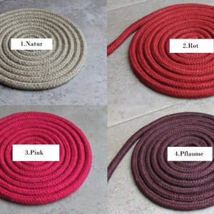 May include: Four coils of braided rope in different colours, each with a white label. The colours are beige labelled 1.Natur, red labelled 2.Rot, pink labelled 3.Pink, and dark plum labelled 4.Pflaume. Each rope is arranged in a tight, circular spiral pattern.