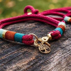 May include: A magenta rope dog collar featuring gold-toned metal hardware, a circular tree of life charm, and decorative thread wrappings in teal, orange, and light blue. The collar includes a sturdy metal clasp and a matching rope leash attachment.
