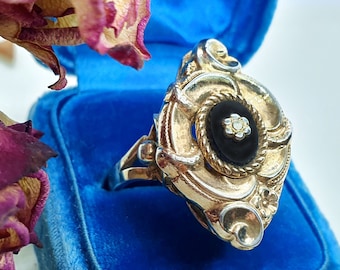 Ausgefallener opulenter Biedermeier Onyx Ring mit goldene Schnörkel Fassung mit ovalen Stein und Blume in der Mitte