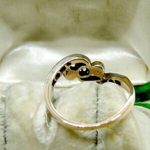 May include: A gold ring with a delicate design featuring a cluster of small stones. The ring is displayed in a green velvet ring box.