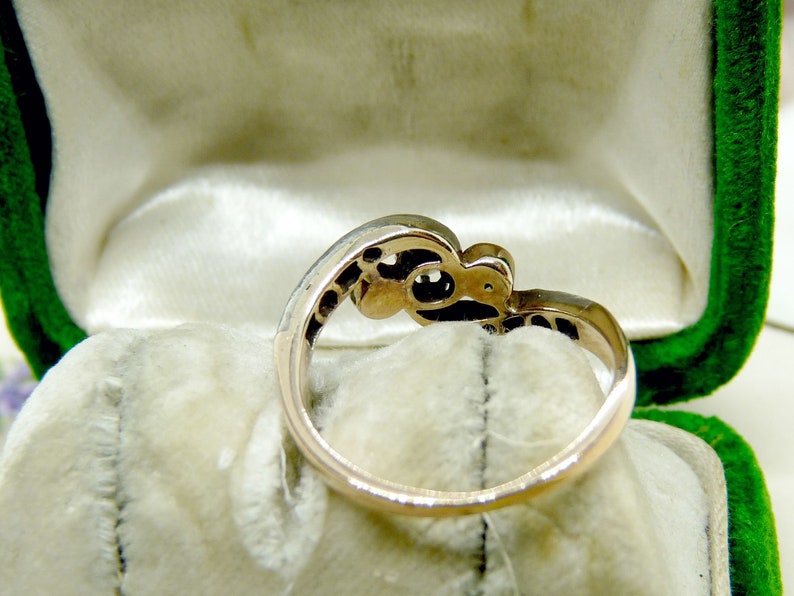 May include: A gold ring with a delicate design featuring a cluster of small stones. The ring is displayed in a green velvet ring box.