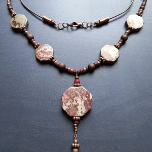 Beaded matinee style necklace with octagonal leopard skin jasper focal and side beads, dark wood and copper accents