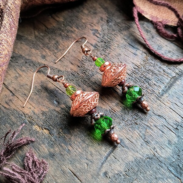 Floral motif on bright copper finished focal beads, complementary green faceted glass beads and antique copper finish findings