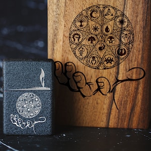 May include: A wooden box with a hand holding a circle of symbols. The box is dark brown and has a natural wood grain. The symbols are black and white and include a star, a circle, a crescent moon, and a sun. The box is sitting on a black surface.