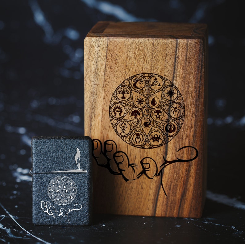 May include: A wooden box with a hand holding a circle of symbols. The box is dark brown and has a natural wood grain. The symbols are black and white and include a star, a circle, a crescent moon, and a sun. The box is sitting on a black surface.