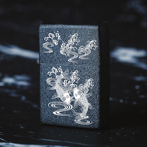 May include: A black lighter with a white design of two koi fish swimming in a wave pattern.