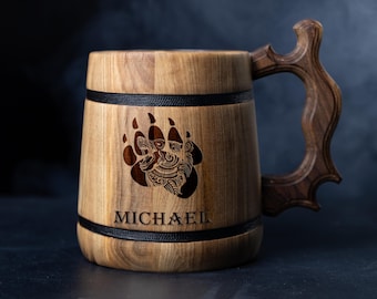 May include: A wooden beer stein with a black leather band and a bear paw print design. The stein has a carved wooden handle and the name "MICHAEL" is engraved on the front.