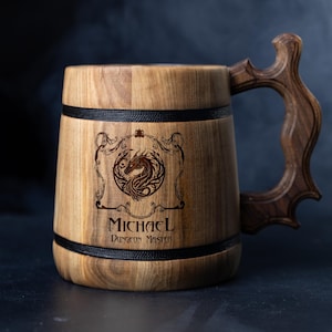 May include: Wooden beer stein with a carved handle. The stein features a dragon emblem and the name "Michael" with "Dungeon Master" below. The mug is made of light brown wood with black accents.