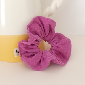 Op de afbeelding: Een roze scrunchie van corduroy.