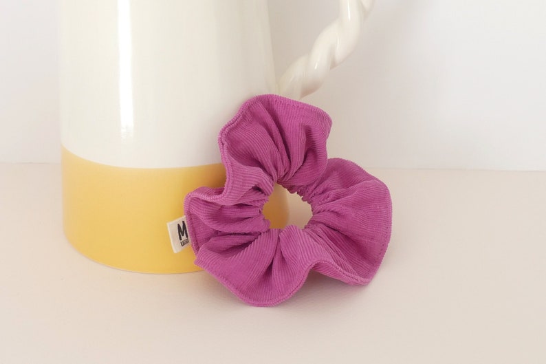 Op de afbeelding: Een roze scrunchie van corduroy.