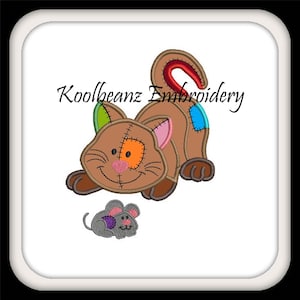 May include: A brown patchwork cat with a pink nose and green, orange, and blue patches on its fur. The cat is lying down with its tail curled up. A small gray mouse with pink ears is lying on the ground in front of the cat. The text "Koolbeanz Embroidery" is written in black above the cat.