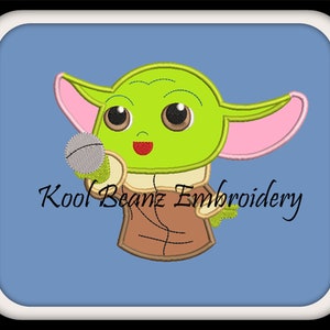 May include: Embroidered design of a green, cartoon character with large eyes, holding a microphone. The character has pink ears and is wearing a brown jacket. The text "Kool Beanz Embroidery" is below the character.