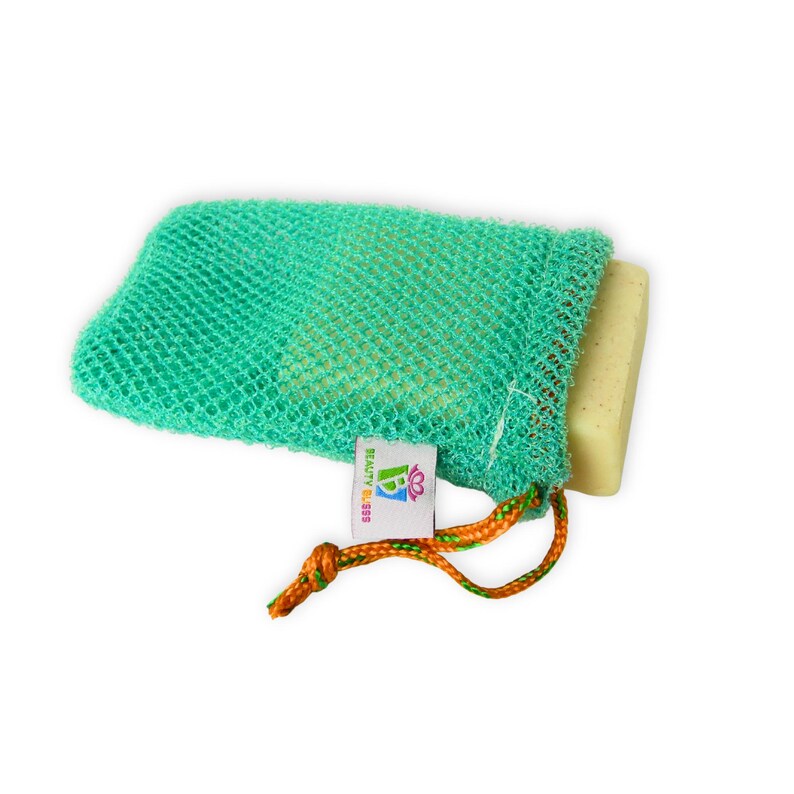 May include: A green mesh soap saver bag with a bar of soap inside. The bag has a drawstring closure with orange and green cord. A small tag with the text "BEAUTY BLISS" is attached to the bag.