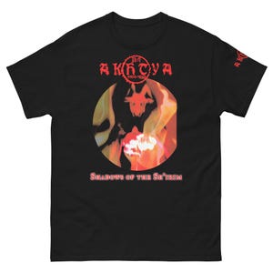 Könnte beinhalten: Schwarzes T-Shirt mit einer roten und orangenen Grafik einer gehörnten Figur in Flammen. Der Text "The Akhtya" und "Shadows of the S'trim" ist in Rot gedruckt.