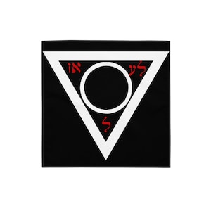 Puede incluir: Textil cuadrado negro con un diseño de triángulo blanco. Dentro del triángulo hay un círculo blanco con un centro negro. Letras hebreas rojas están colocadas alrededor del círculo.