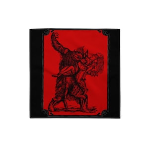 Op de afbeelding: Zwarte en rode bandana met een gedetailleerde illustratie van een weerwolf die een persoon draagt. Het kunstwerk is in vintage stijl, met het ontwerp tegen een rode achtergrond en omlijst door een zwarte rand.