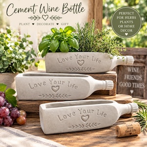 May include: Three light gray cement planters shaped like halved wine bottles. Each planter features the embossed text Love Your Life, a heart icon, and a leafy branch design. The planters are arranged on wooden surfaces with green herbs.
