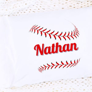 May include: White pillowcase with a red and black baseball graphic and the name "Nathan" in red text.