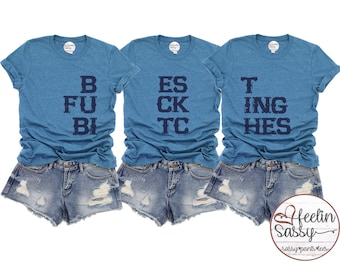 May include: Three blue t-shirts with white text that reads "B FU BI", "ES CK TC", and "T ING HES".