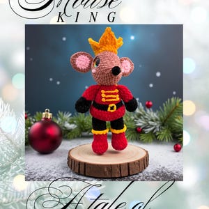 May include: Crocheted Mouse King doll wearing a red jacket with gold trim, black pants, and red boots. The mouse has a gold crown and pink ears. The doll is displayed on a wooden slice with a Christmas ornament and greenery in the background. The text "Mouse King" and "A Tale of Yarnia" are also visible.