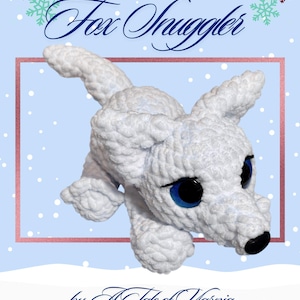 May include: A white crocheted arctic fox toy with blue eyes and a black nose. The text "Felix the Arctic Fox Snuggler" is displayed above the fox, with the phrase "by: A Tale of Yarnia" below. The background is light blue with snowflakes.