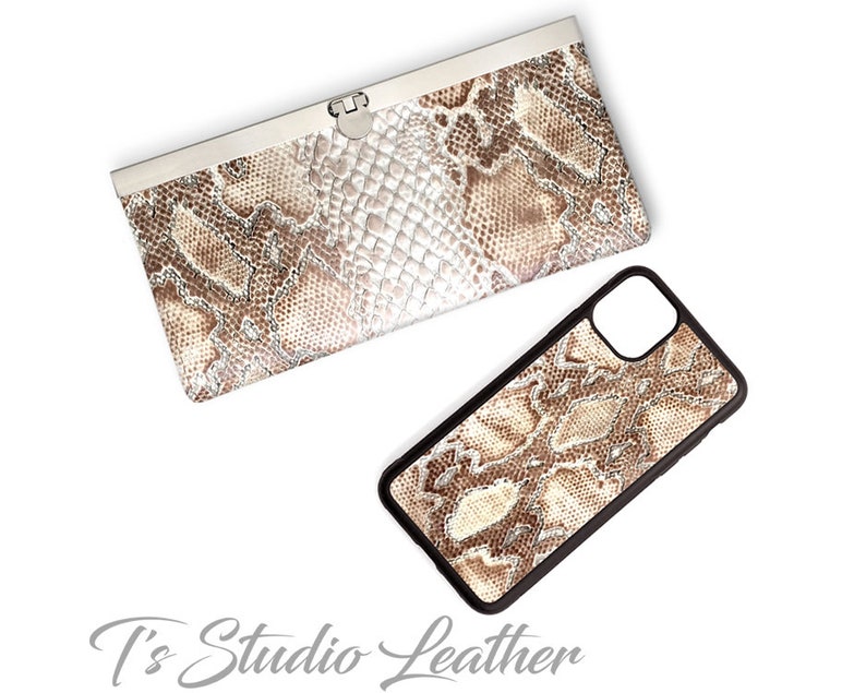 Może przedstawiać: Brązowy i biały portfel ze sk&oacute;ry węża z srebrnym zapięciem i pasujące etui na telefon ze sk&oacute;ry węża w kolorze brązowym i białym.