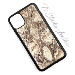 May include: A black phone case with a snakeskin pattern in shades of brown and beige. The case has a cutout for the camera lens.