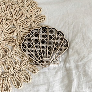 May include: A wooden seashell wall decor with a woven pattern. The seashell is light brown and has a natural wood finish.